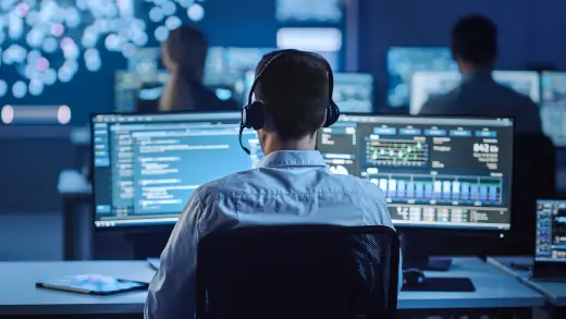 it-leitstelle mann vor zwei bildschirmen it-support