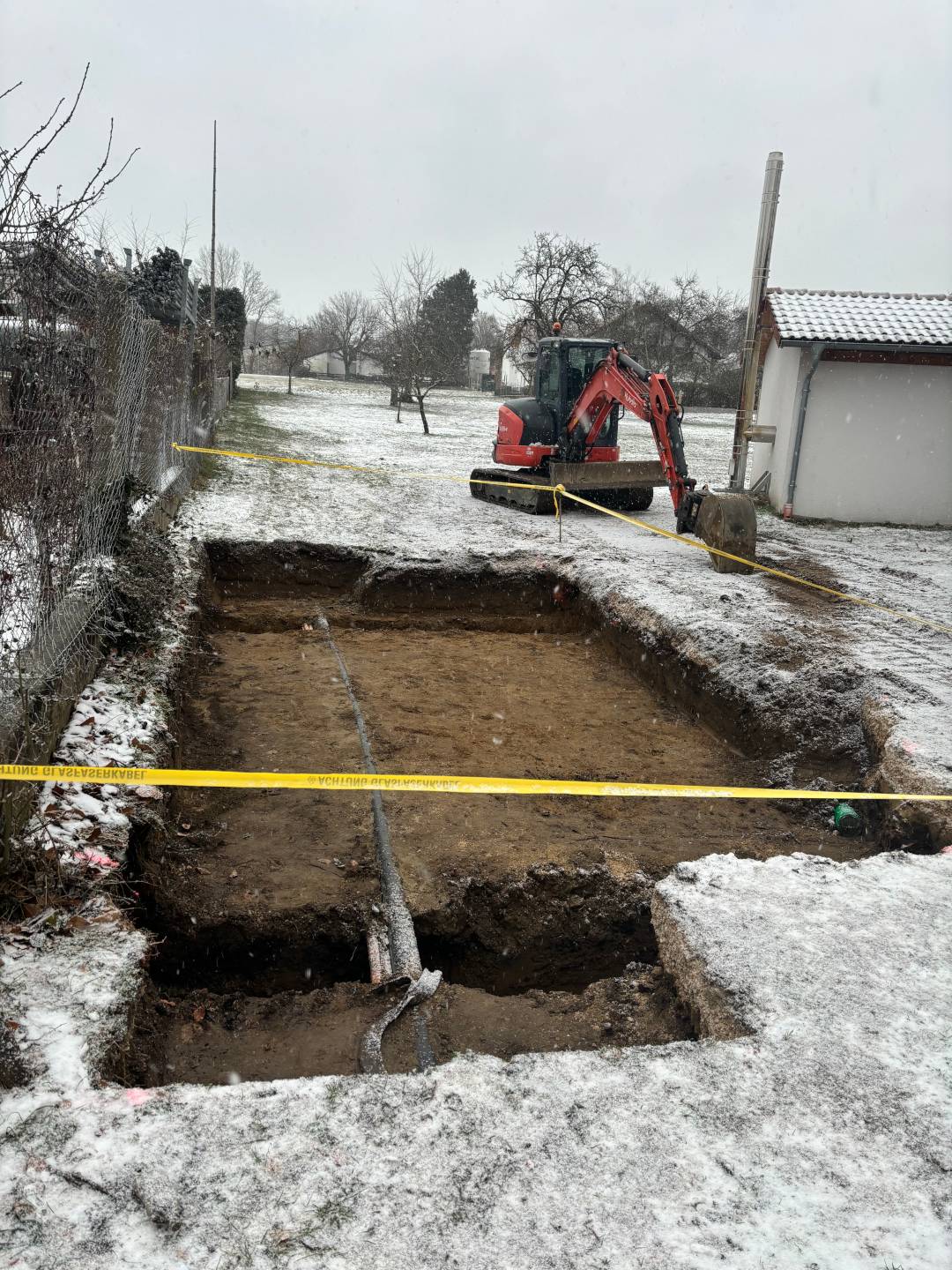 glasfaserausbau-bayern-verteilerbau-aresing-01 Glasfaserausbau Bayern: Baggerarbeiten für Verteilerbau in Aresing mit ausgehobener Baugrube und Minibagger im Winter